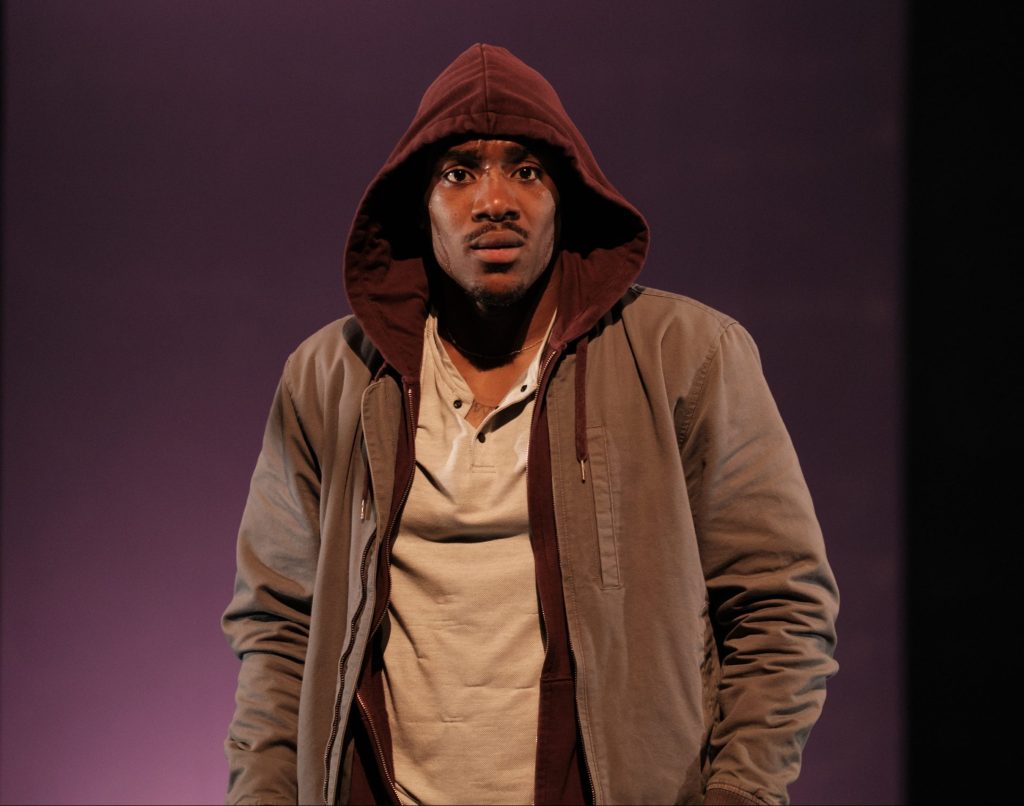 Young Black man looking at camera in a hoodie.